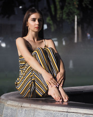 Girl brunette model sitting near with fountain