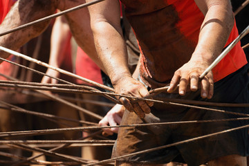 Mud race runners,racers overcome the obstacle from the ropes