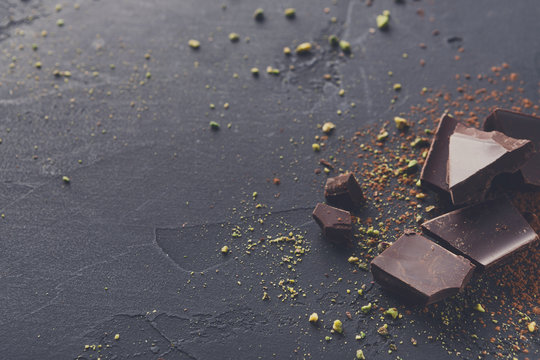 Broken Chocolate Pieces And Cocoa Powder On Black Background
