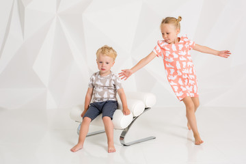 Brother and sister playing and smiling in a white studio