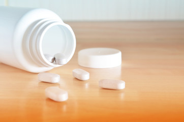 Fototapeta na wymiar Pharmacy theme. White bottle of pills on a wooden surface. Closeup.