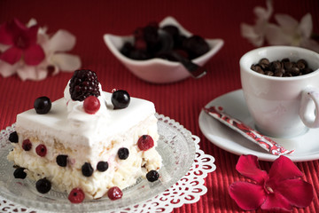 Ein Stück Sahnetorte mit Beeren und einen Tässchen Kaffee