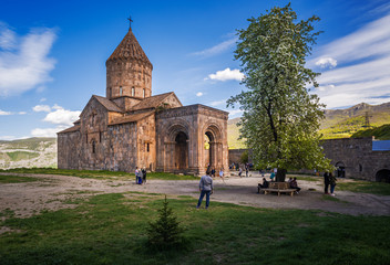 Ancient Armenian monastery Tatev. Church in mountains. Tourists on guided tour. Landscape.
