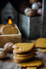 Pile of home baked Christmas gingerbread cookies in wood box, burning candle, pine cones and colorful baubles, rustic kitchen interior, festive atmosphere