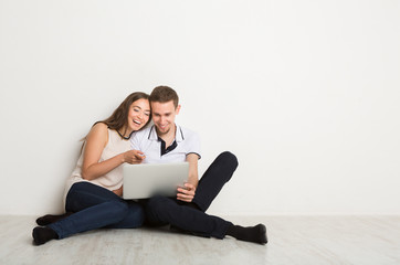 Cheerful couple using laptop at home, copy space