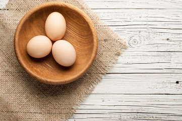 chicken eggs in wooden plate on white wooden background