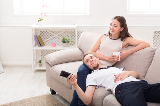 Smiling young couple watching TV at home