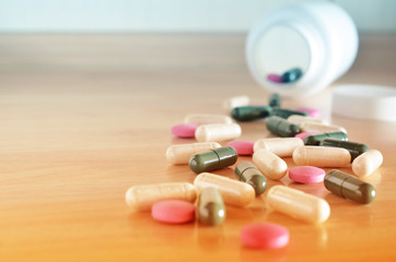 Pharmacy theme. White bottle of multicolored pills on a wooden surface. Closeup.