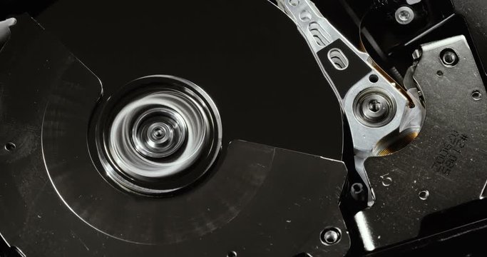 HDD reading and writing data. Operating hard disk drive on dark background.