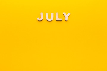 Word July on yellow background