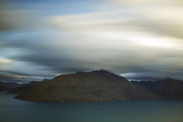 A long exposure shot of clouds passing over mountains.