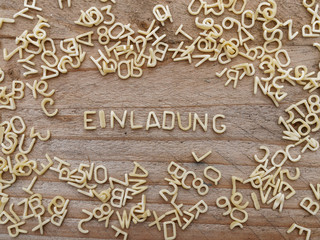 EINLADUNG - Buchstabennudeln auf Holzbrett