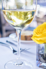 Glass of White Wine and a Yellow Rose on a Restaurant Table
