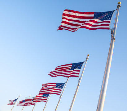 United States of America Flags Blowing in the Wind and Against the Blue Sky