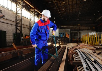 Portrait of a handsome young factory worker in a white construction helmet with a large bolt cutter in hand on an industrial background