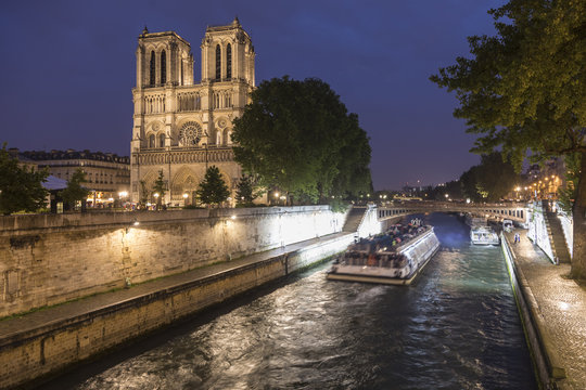 Tourboat passing Notre Dame Cathedral at night, Paris, France