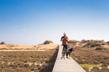 Man walking with his dog on a road leading through beautiful landscape