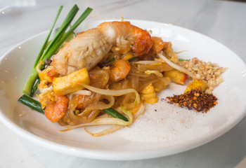 Fried Rice Sticks with Shrimp (PAD THAI GOONG SOD) put a white plate and placed on a white marble table.This is a popular food to eat when coming to Thailand.