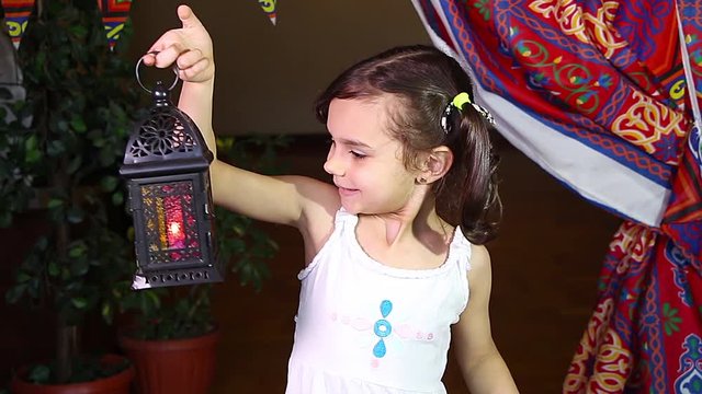 Ramadan Kareem - Young girl smiling and holding Ramadan lantern