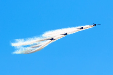 Group of white turboprop airplane with a trace of white smoke against a blue sky