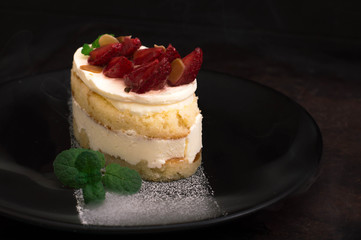 Strawberry cake with almond petals. Old black background. Close-up. Top view