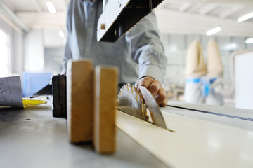 Hand carpenter on the background of a circular saw and wooden bars. Joinery