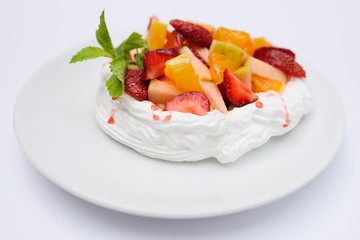 Dessert with cream, strawberries, oranges, apples and mint on white background