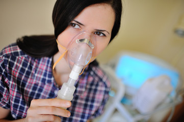 Adult pretty girl with inhaler in the clinic