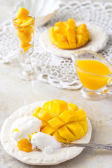 Ice cream and Mango fruit half cubes and mango juice puree on white Concrete background. Tropical fruit concept. Vegan food