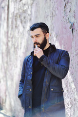 Bearded young man smokes an electronic cigarette or vape