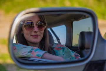 Young woman driver in the car looking to the side view mirror