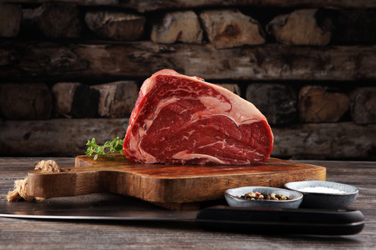 Raw fresh meat Ribeye Steak, seasoning and meat fork on dark background