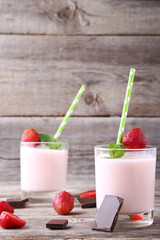 Strawberry yogurt in glass on grey wooden table