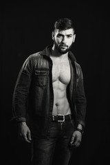 Fototapeta na wymiar Young handsome muscular man with a beard, posing on a black background