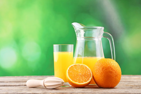 Glass jug with orange juice on wooden table