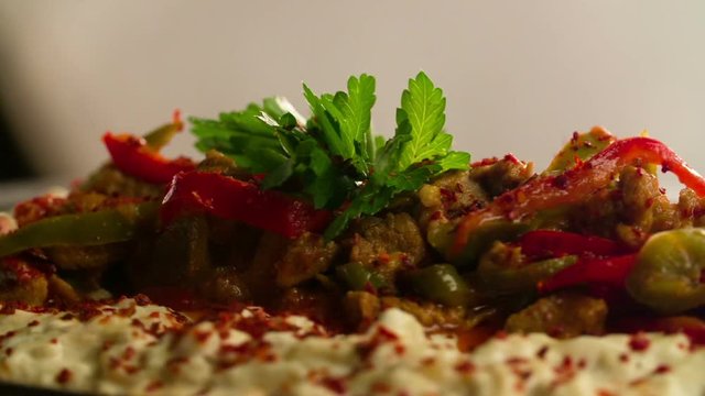 crushed chili pepper poured over Turkish Hunkar Begendi Kebab slow motion