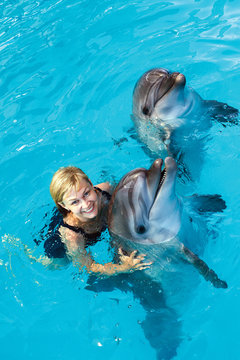 Coach swims in the water with dolphins. Dolphin Assisted Therapy