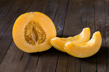 Half melon and slices on a dark wooden background