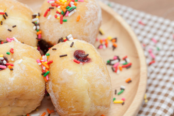 a variety of jam doughnut on wooden plate with sprinkles