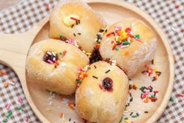 a variety of jam doughnut on wooden plate with sprinkles