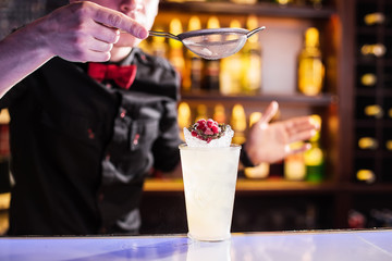 The barman decorates the cocktail behind the bar