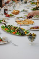 Hand with tongs keeping pieces of fish during banquet.