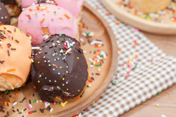 a variety of doughnut on wooden plate with sprinkles