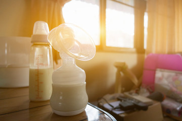 Automatic breast pump, mothers breasts milk is the most healthy food for newborn baby. Happy mother with babys at bed room ,home,vintage color