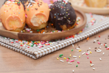 a variety of doughnut on wooden plate with sprinkles