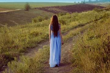 Obraz premium Brunette walking on the road at sunset in the evening