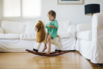 1 year old boy playing with his toy horse