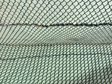 Close up of chain-link fence and long shadows