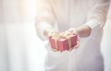 Closeup, Woman hand holding red gift box with copy space background, female giving gift, New year...