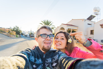 Obraz premium Funny couple With Keys Standing Outside New Home. Real estate, owner and people concept